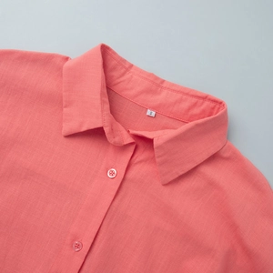 Detailed macro view of coral cotton shirt collar with resin button and size S label