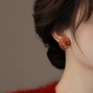 Macro shot of red enamel flower earrings with gold hollow texture on model
