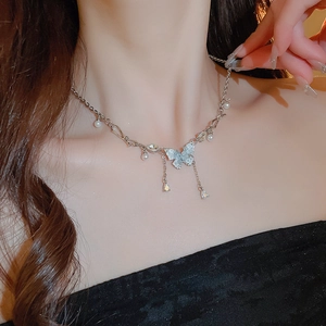 Dettaglio della collana a farfalla argentata con nappe di cristallo e perle sul collo