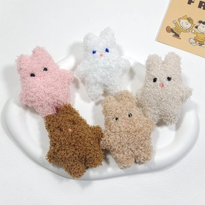 Detailed view of five plush rabbit brooches in assorted colors on a cloud-shaped tray