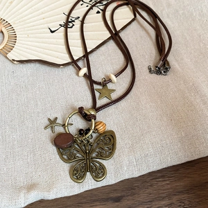 Retro wax cord necklace with wooden beads and butterfly pendant on linen background