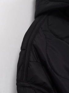 Detail shot of black quilted jacket shoulder showing fine stitching and premium fabric texture