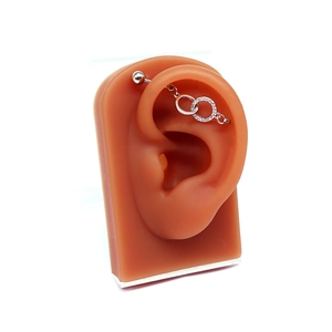 Vue détaillée du piercing industriel argenté avec doubles anneaux en cristal sur modèle