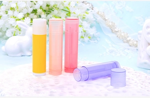 Close-up of four colorful plastic 5g lipstick tubes on white lace for DIY cosmetics