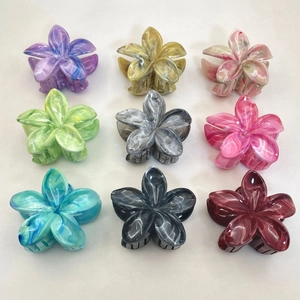 Set of nine colorful plumeria flower hair claws in a variety of marbled resin finishes