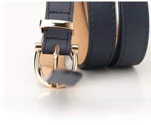 Detail of navy blue PU leather belt with polished gold buckle and fine stitching