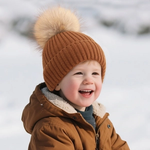 Warm caramel brown kids winter beanie featuring ribbed knit texture and a large faux fur pom