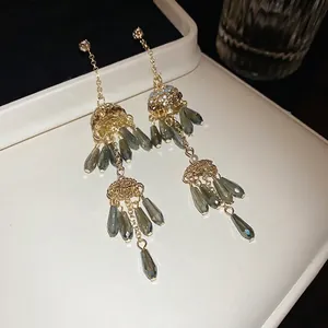 Bohemian gold tassel earrings with green teardrop beads and pearls on display