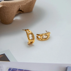 Detailed close-up of twisted gold stainless steel earrings with oval zircon inlay