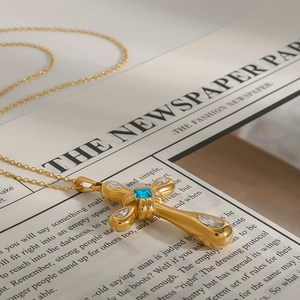 Detailed macro view of a gold cross necklace with blue sapphire and white zircon stones