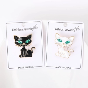 Detail of cat brooches with green gemstone eyes and gold trim in black and white
