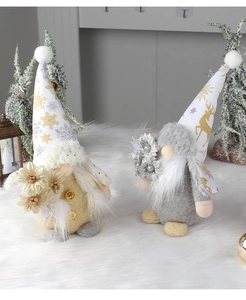 Close-up of plush Christmas gnomes with gold and silver hats on white faux fur