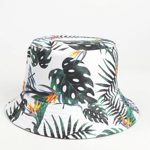Detail view of a white sun hat featuring vibrant tropical green palm leaves and floral prints