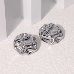 Macro detail of silver stainless steel stud earrings with irregular wrinkled texture