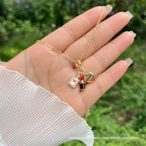 Dettaglio collana placcata oro 18K con boccetta di profumo in zircone, rossetto e ciondoli