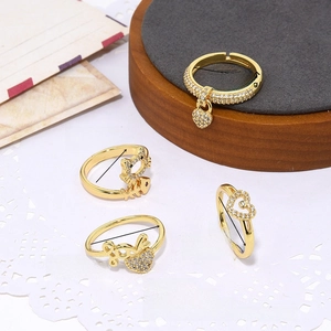 Dettaglio di anelli placcati oro 18K con ciondoli a cuore, gatto e lisca di pesce