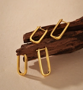 Macro detail of gold S925 sterling silver U-shaped hoop earrings on dark wood