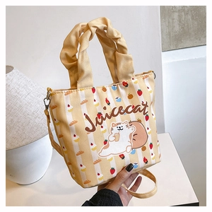 Detail of yellow striped canvas bucket bag with cute cat illustration and ruffle handle