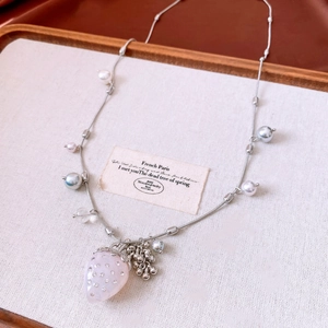 Detail of pink strawberry pendant with rhinestones and colorful pearls on a silver chain