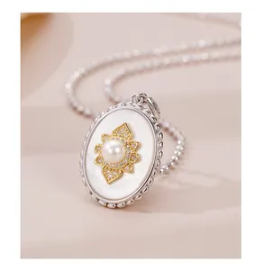 Detailed close-up of oval mother of pearl pendant with centered pearl and gold accents