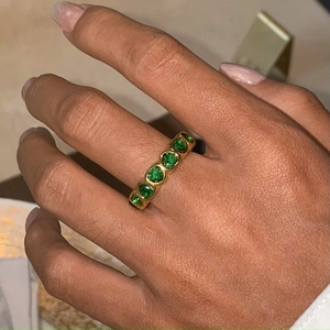 Close-up of gold stainless steel ring featuring multiple green heart-shaped gemstones
