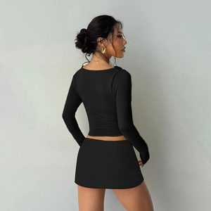 Detail view of black long-sleeve crop top and mini skirt set with slim-fit knit texture