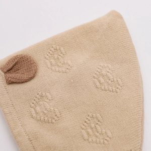 Detail of soft beige knit baby hat featuring raised heart patterns and cute 3D ears