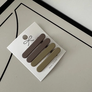Close-up of matte coffee and olive hair clips set on white card with bow icon