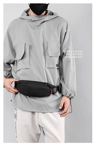 Close-up of black nylon mini messenger bag with red accents on grey streetwear hoodie