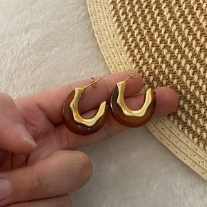Vintage C-shape hoop earrings with amber resin and gold stainless steel in a hand-held shot