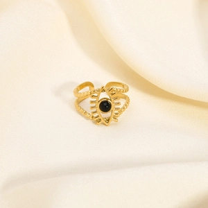 Macro shot of gold devil eye ring with black stone on white silk background