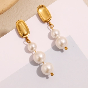 Détail de boucles d'oreilles asymétriques plaquées or 18K avec perles blanches dégradées