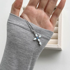 Close-up of S925 silver cross pendant with white opal stones and blue central gem