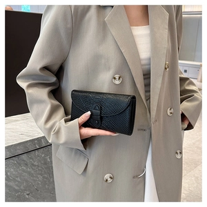 Macro detail of black crocodile pattern leather texture on a stylish women's wallet