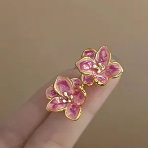 Macro shot of pink-purple gradient flower earrings with gold edges and white detail