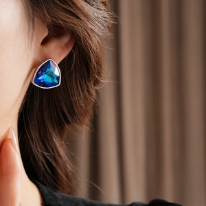 Gros plan d'un modèle portant des boucles d'oreilles triangulaires bleues en argent