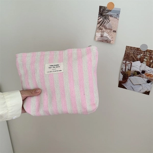 Close-up of a pink striped fabric toiletry bag with woven texture and zakka label