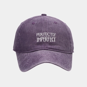 Detail of purple washed cotton baseball cap with Perfectly Imperfect white embroidery