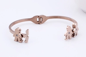 Close-up of rose gold bangle featuring charming boy and girl charms with a hinged clasp