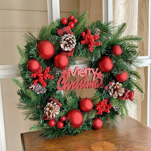 Weihnachtskranz mit roten Beeren, Zapfen und Merry Christmas Schild auf Holztisch