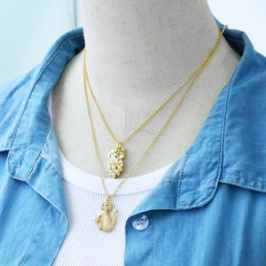 Close-up of owl and cat pendants with pearls and rhinestones on gold layered chains