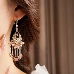Close-up of golden tassel earrings with pink beads and sparkling crystal zircons