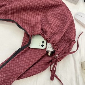Detail of red checkered nylon bag with black zipper and drawstring pleated texture