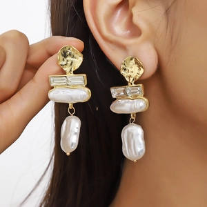 Detailed close-up of Baroque pearl earrings featuring hammered gold metal and crystal accents