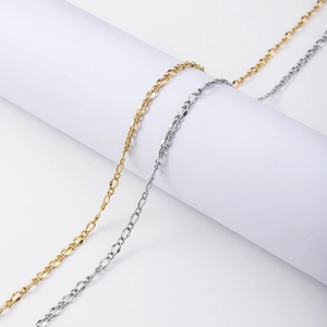 18k gold and silver stainless steel flat curb link chains on a white cylinder stand