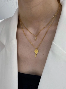 Detailed close-up of double-layer gold necklace with letter R pendant and key charm
