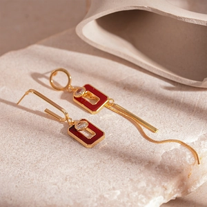 Detail of vintage geometric earrings with red resin inlay and elegant long metal tassels