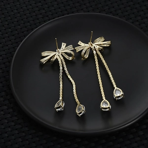 Detailed shot of golden bow earrings with long tassels and teardrop-shaped zircons