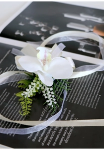 Detail of white artificial orchid wrist corsage with silk ribbons on a fashion magazine