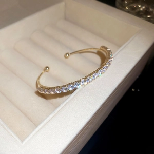 Macro shot of gold adjustable bangle with pavé-set zircons on a beige velvet jewelry box